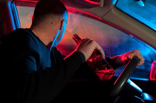 man driving with bottle of alcohol in his hand